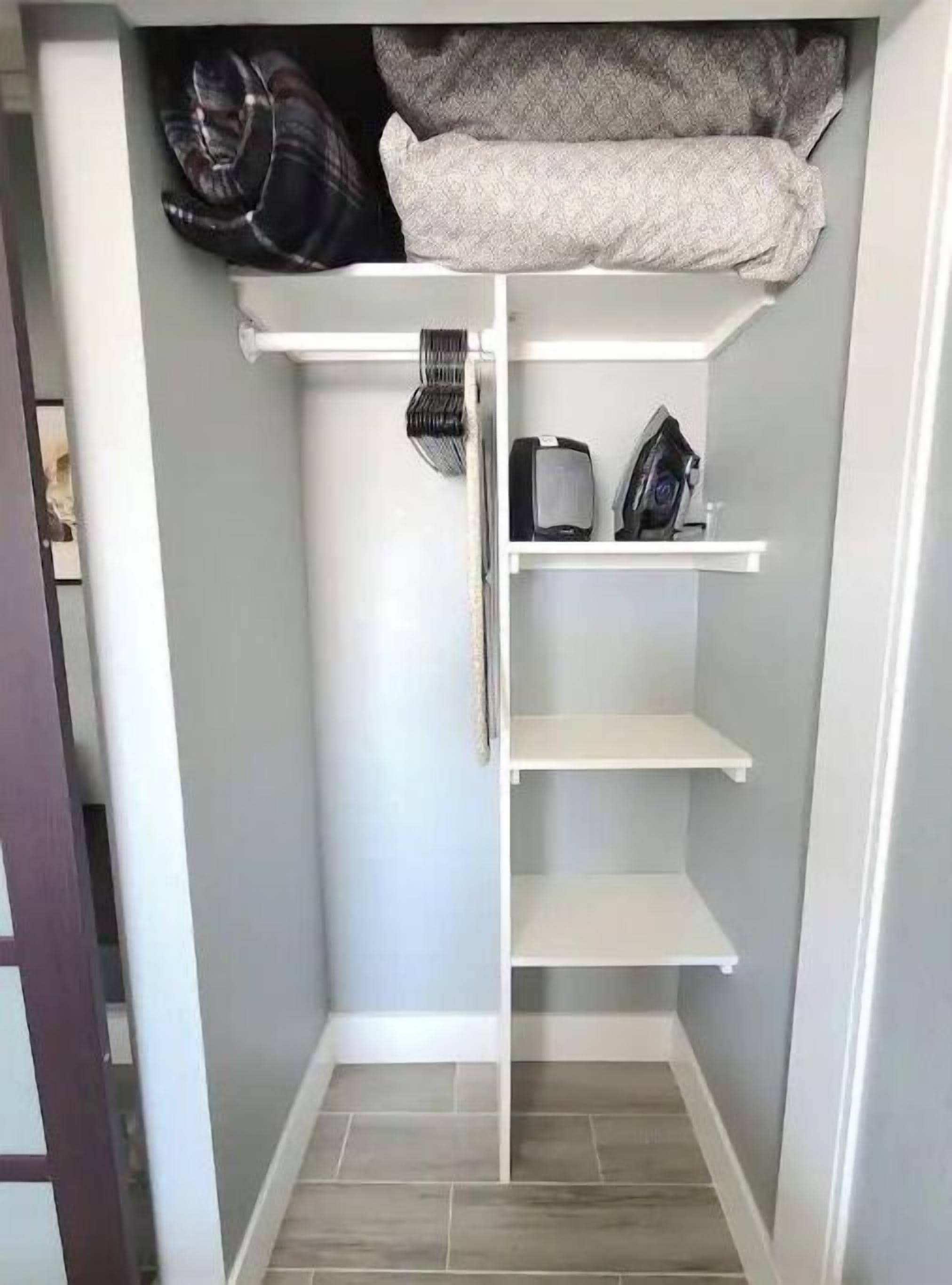 A small, enclosed storage space with shelves and a hanging rack.