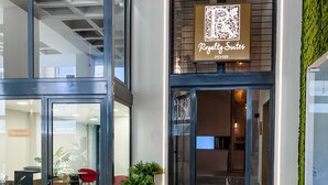 A hotel entrance with a reception desk, a QR code sign, and a reception area visible through the glass doors. - Royalty Suites Psyrri (Athens)