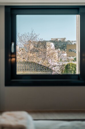 A window view of a building with a tiled roof and trees in the foreground. - Royalty Suites Psyrri (Athens)
