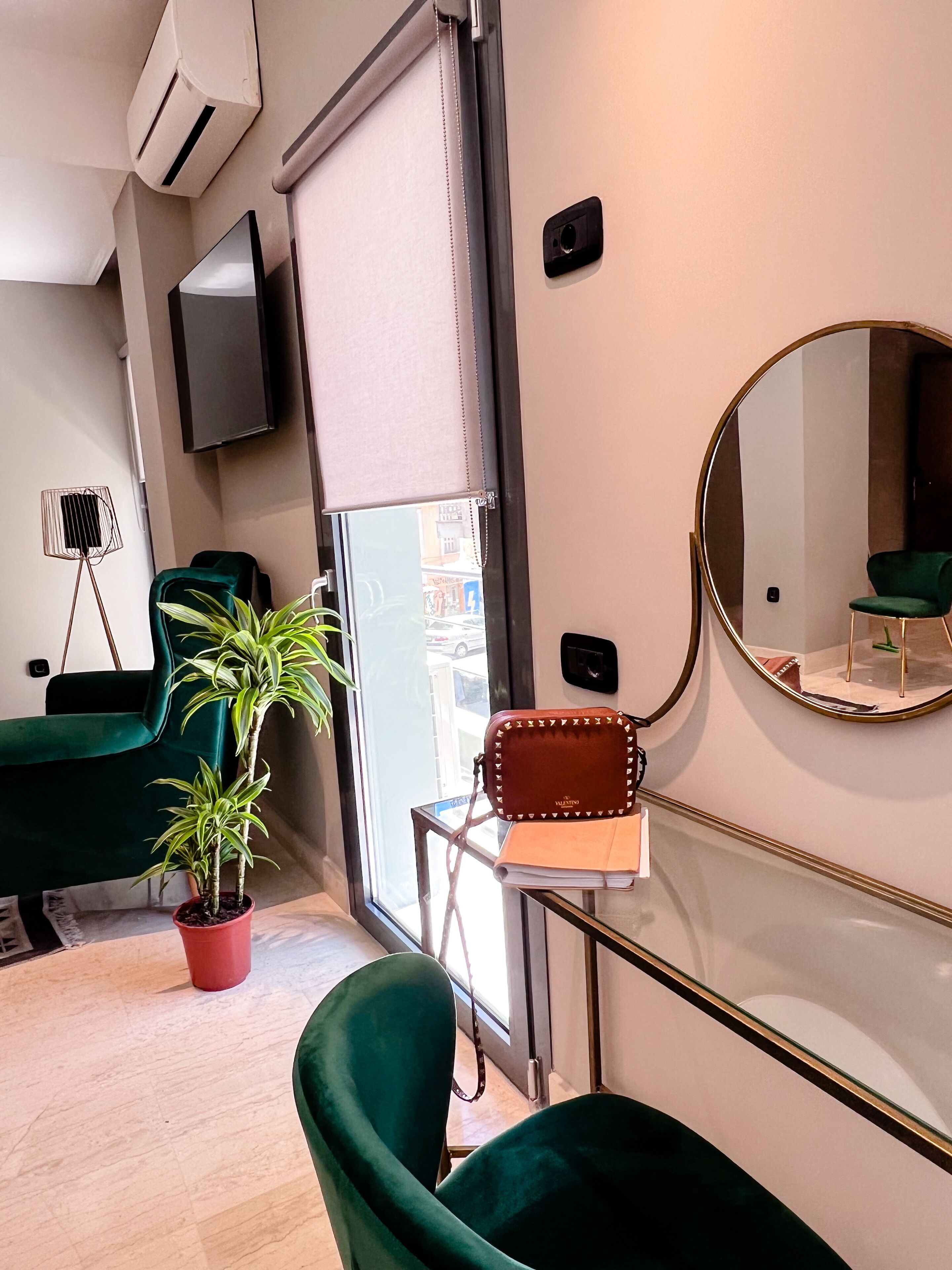 Een moderne kamer met een grote spiegel, een kamerplant en twee groene stoelen.