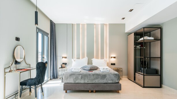 A modern bedroom with a bed, bedside tables, a desk, a chair, and a wardrobe. - Royalty Suites Psyrri (Athens)