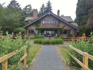 A restaurant with a wooden exterior, a gravel pathway leading to the entrance, and a garden with plants and a wooden fence.