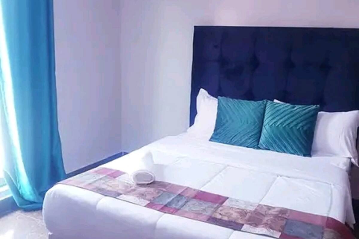 A hotel room with a large bed, a headboard, and a window with curtains.