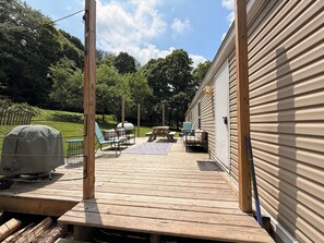 Eine Holzterrasse mit Gartenmöbeln, einem Grill und einem überdachten Grillbereich.