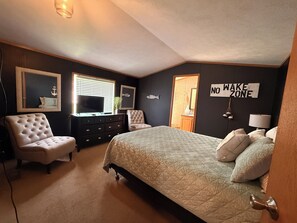 Ein Schlafzimmer mit einem Bett, zwei Stühlen, einer Kommode, einem Fernseher und einem Schild mit der Aufschrift 'NO WAKE ZONE'.