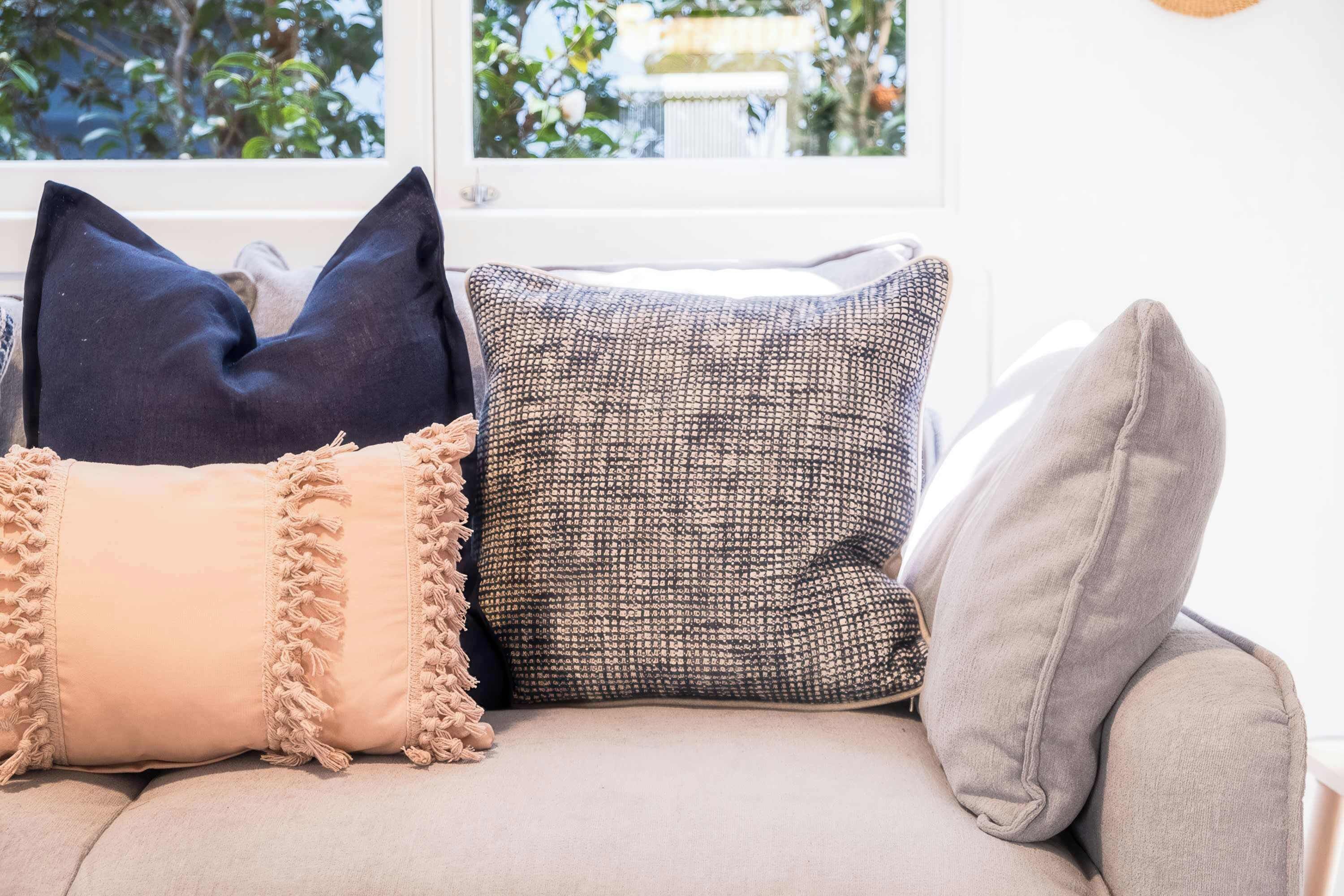 Un canapé agrémenté de trois coussins aux textures et aux motifs différents.