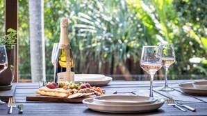 A table set with a bottle of Brut champagne, two glasses of wine, and a variety of snacks. - The Otto at Moffat Beach (Moffat Beach)