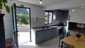 A modern kitchen with grey cabinets, a built-in oven, and a dining area with a wooden table and chairs.