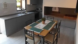 A modern kitchen with grey cabinets, a wooden dining table with four chairs, and a small island with a sink.