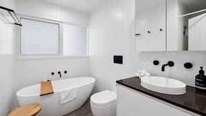 A modern bathroom with a freestanding bathtub, a toilet, and a vanity with a sink. - Anglesea Beach House 2 (Anglesea)