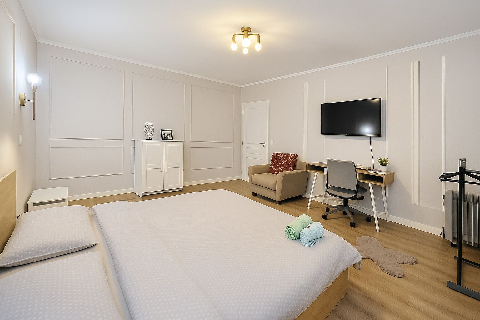 Et hotelværelse med en stor seng, et skrivebord med stol, et fjernsyn og et klædeskab.