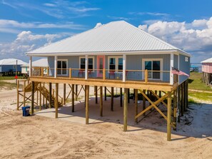 A beach house with a wooden deck, a red door, and a view of the ocean. - Gulf View! 4 bathrooms! New Construction! - Southern Ties (Dauphin Island)