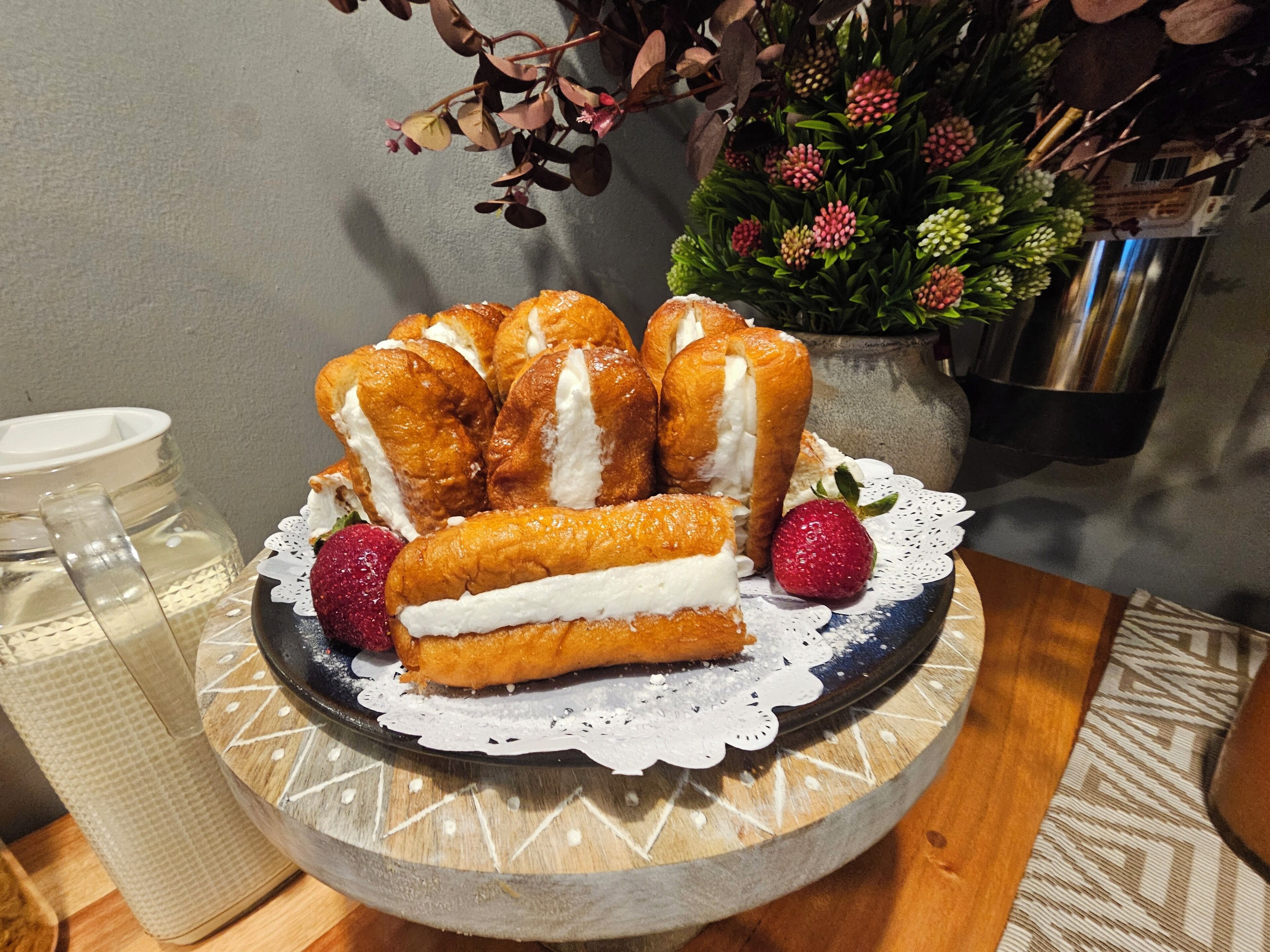 A plate of cream puffs on a decorative plate with a lace doily.