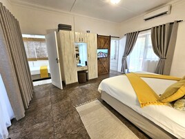Habitación de hotel con cama, armario, televisor y vista al exterior.