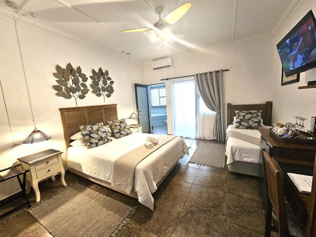A hotel room with a bed, a desk, a chair, a television, and a window with curtains.
