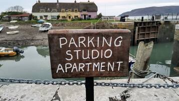 Schild für ein 'PARKING STUDIO APARTMENT' mit Blick auf Boote und ein Gebäude im Hintergrund.