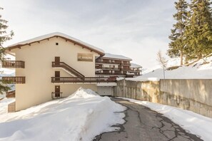 Ein Hotel mit der Aufschrift "LE VANOISE", ein mehrstöckiges Gebäude mit Balkonen vor einer verschneiten Landschaft.
