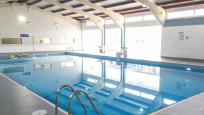 En indendørs swimmingpool med tydelige baner, et lavvandede område og en redningsbøjes vogterstation.