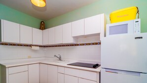 A kitchen with white cabinets, a sink, a stove, and a microwave. - Jewel in the sky, joy on the beach: beachfront penthouse, views of El Yunque (Luquillo)