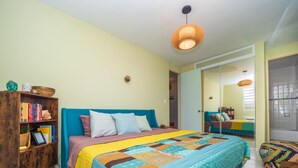 A bedroom with a large bed, a wooden bookshelf, and a bathroom with a shower and a mirror. - Jewel in the sky, joy on the beach: beachfront penthouse, views of El Yunque (Luquillo)