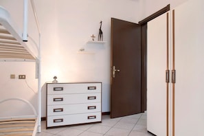 Une chambre à coucher comprenant un lit, une commode, une armoire et une étagère avec des objets décoratifs.