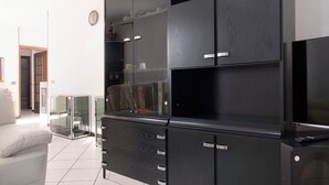 Ein modernes Wohnzimmer mit einer großen, schwarzen Unterhaltungsecke, einem weißen Sofa und einer Glastrennwand.
