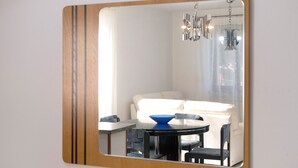 Ein Zimmer mit einer Spiegelwand, einem runden Tisch mit Stühlen, einer blauen Schüssel und einem weißen Sofa.