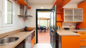 A modern kitchen with a stainless steel sink, a built-in oven, and a dining area with a table and chairs. - Villa 'Pepa' with Sea Views, Heated Pool, and Wi-Fi (Chilches)