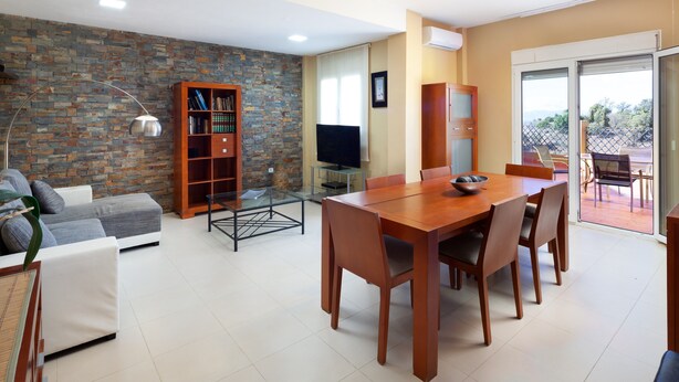 A modern living room with a dining area, a bookshelf, a flat-screen TV, and a view through a sliding glass door. - Villa 'Pepa' with Sea Views, Heated Pool, and Wi-Fi (Chilches)