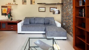 A modern living room with a sectional sofa, a glass coffee table, a wooden bookshelf, and a brick accent wall. - Villa 'Pepa' with Sea Views, Heated Pool, and Wi-Fi (Chilches)