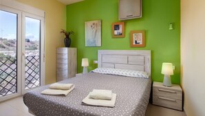 A bedroom with a bed, two bedside tables, a dresser, and a window with a view. - Villa 'Pepa' with Sea Views, Heated Pool, and Wi-Fi (Chilches)