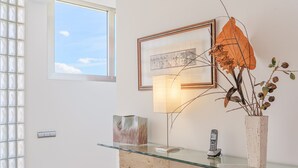 A reception area with a glass desk, a framed picture, a lamp, and a vase with dried plants. - Villa Agusmar with Sea View, Pool & Wi-Fi (llucmajor)