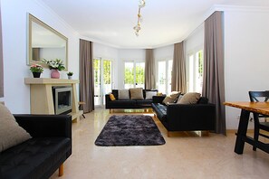 A modern living room with a fireplace, two sofas, a dining table, and large windows. - Villa 'Casa Isabella Luxury' with Sea View, Wi-Fi and Air Conditioning (Nerja)