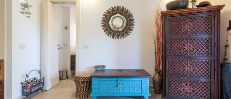 Una habitación con un aparador azul, un espejo decorativo y un mueble de madera con motivos de estrellas.