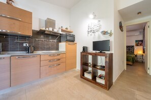 Una cocina moderna con armarios de madera, horno empotrado y televisor sobre un mueble de madera.