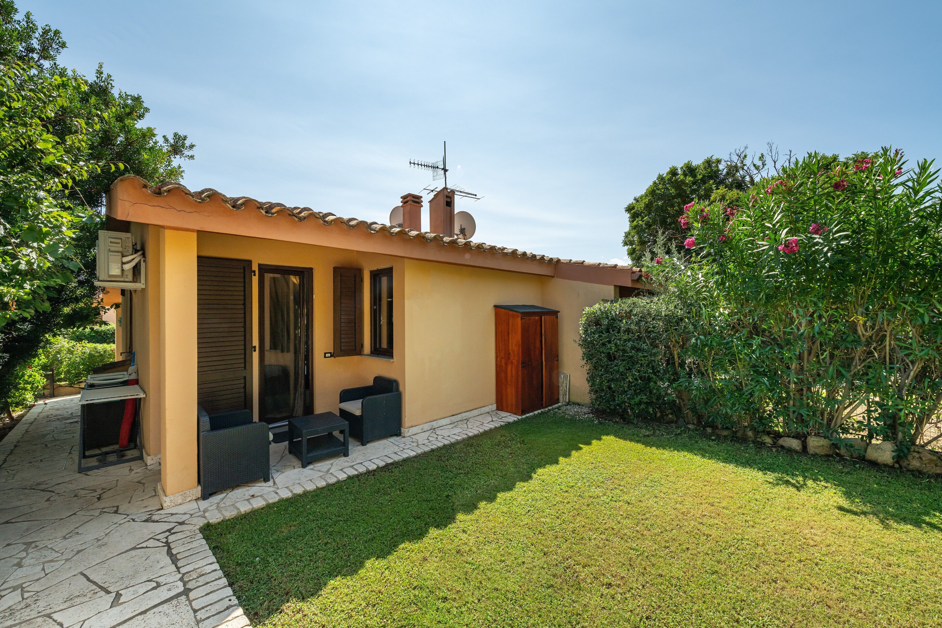 Ein Haus mit Terrasse, einer Tür und einem kleinen Garten.