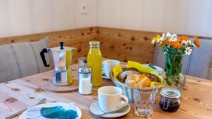 A wooden table with breakfast items, a coffee pot, a glass of juice, a jar of jam, a vase with flowers, and a basket of bread. - Holiday Apartment Hof im Thal Apt Linde with Mountain View, Balcony & Wi-Fi (Aldino)