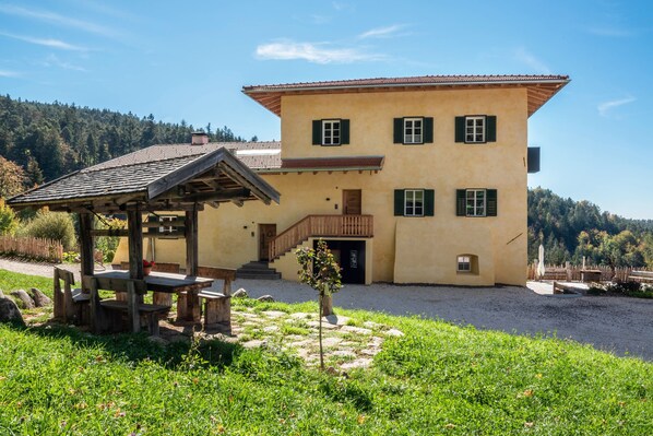 Ein zweistöckiges Gebäude mit einer Holzpergola, einer Treppe und einem kleinen Baum im Innenhof.
