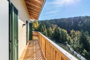 Eine Holzterrasse mit Blick auf einen bewaldeten Hügel.