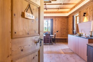A wooden interior with a door labeled 'Zirbe,' a dining area, and a kitchen with a window.