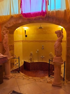 A bathroom with a tiled floor, a shower area, and two statues.
