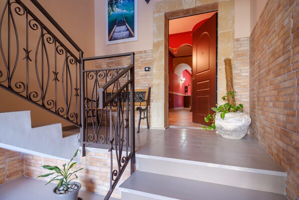 A staircase with a wrought iron railing, a potted plant, and a stone planter.