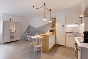 Eine moderne Küche mit weißen Schränken, einer Holzinsel und einem Essbereich mit weißen Stühlen.