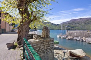 Une scène de bord de mer avec un mur de pierre, un arbre et des bateaux amarrés à un quai.