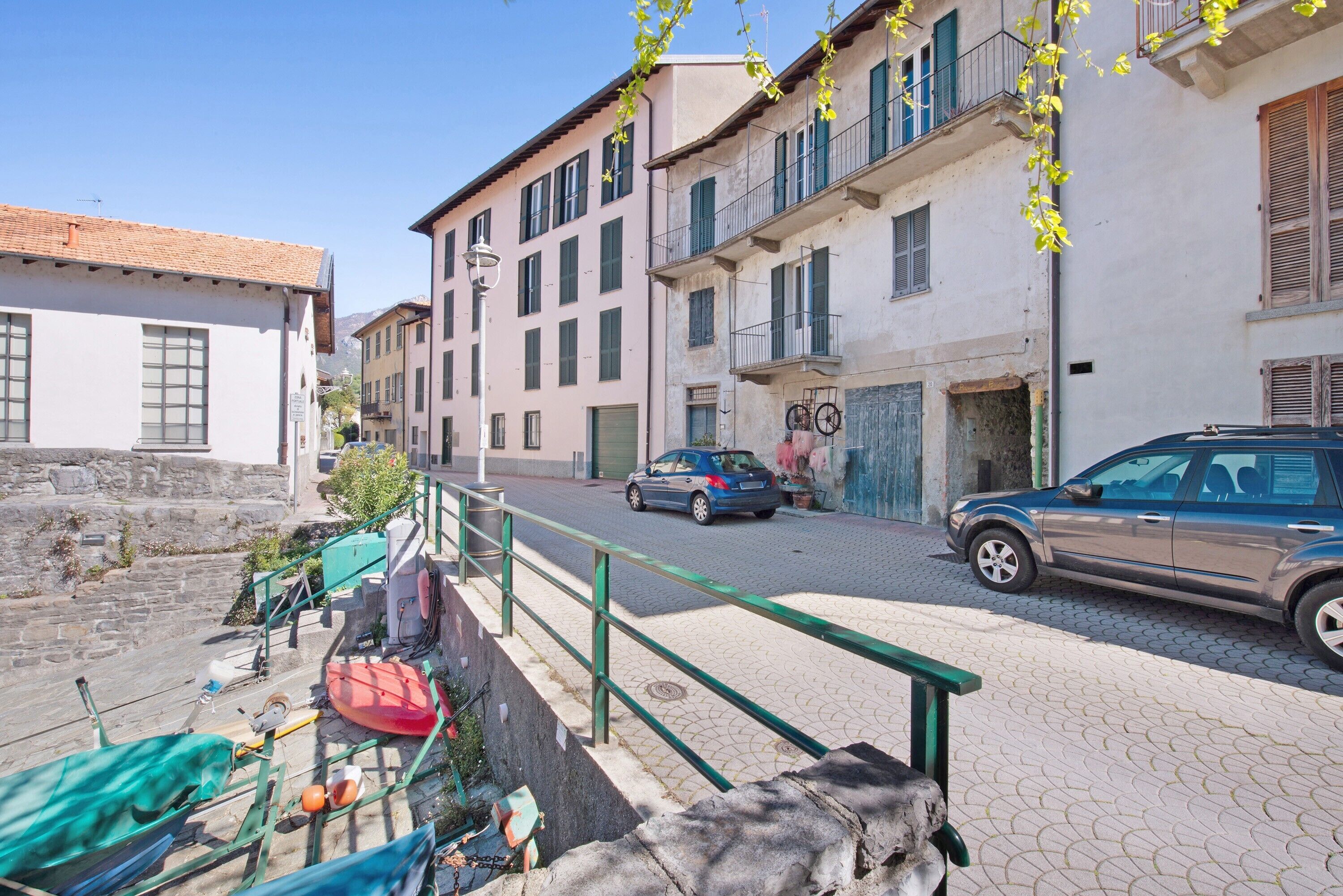 A street with buildings, a parked car, and a bicycle.