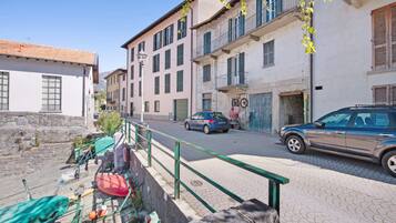A street with buildings, a parked car, and a bicycle.
