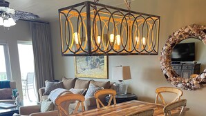 Zona pranzo con tavolo e sedie in legno, un lampadario, un televisore e uno specchio decorativo.