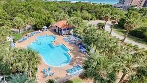 Un resort con una grande piscina circondata da palme e lettini.
