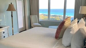 Camera d'albergo con un letto grande, una sedia, una scrivania e vista sull'oceano.