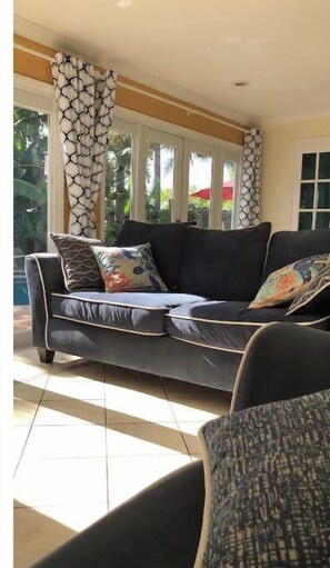 Relax in a stylish room with a sofa set against a wall of large windows, patterned curtains, and a comfortable chair.